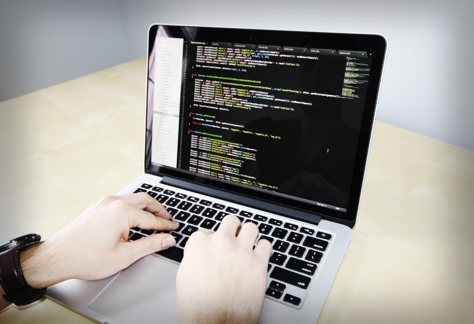 Hands typing code on a laptop