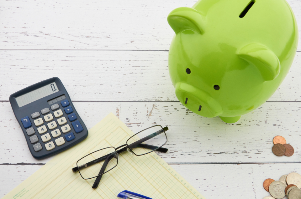 A piggy bank, calculator and budget worksheet on a table