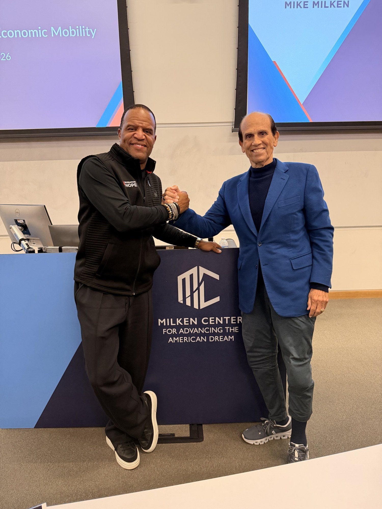 John Hope Bryant and Michael Milken standing together at the Milken Center for Advancing the American Dream lectern at USC