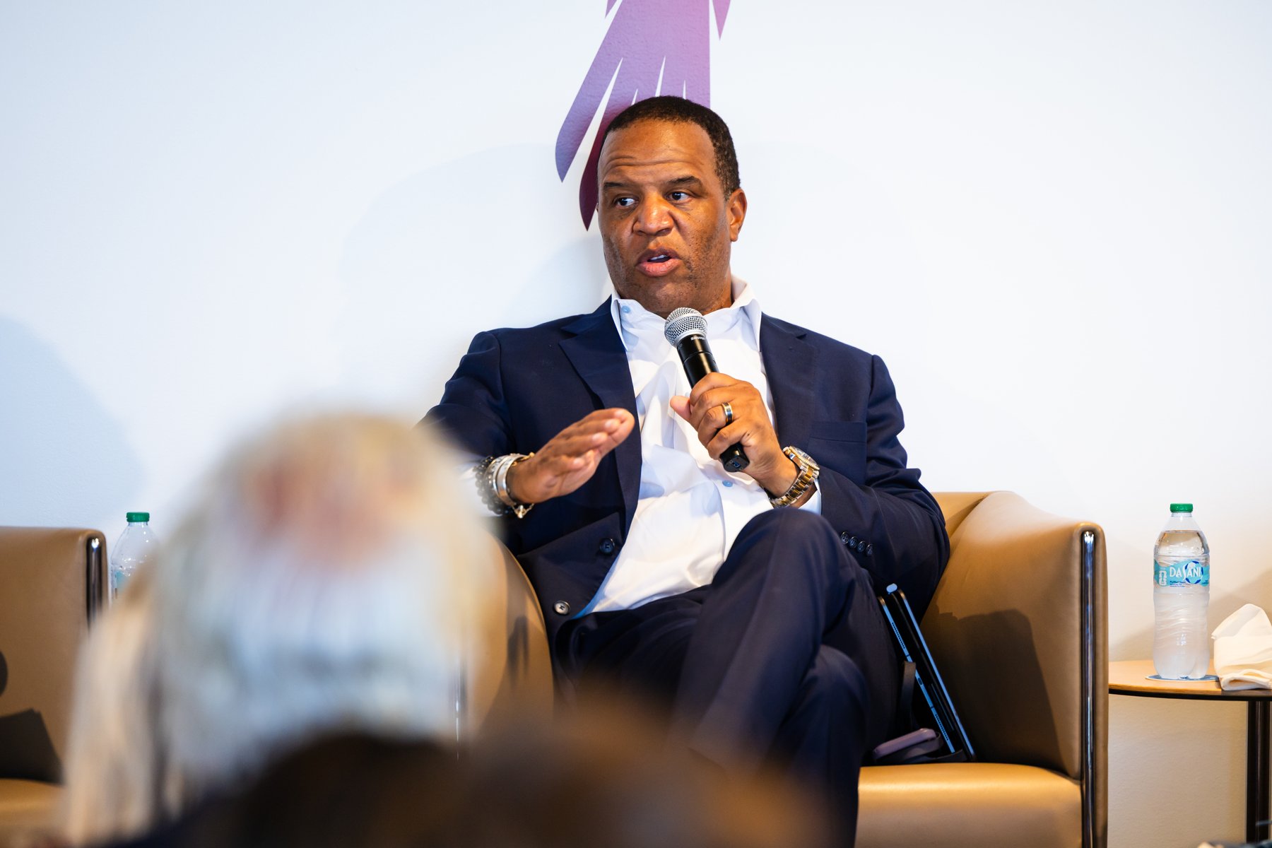 John Hope Bryant speaking with a microphone while seated in an armchair
